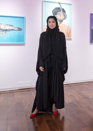 Woman standing wearing Abaya and red shoes