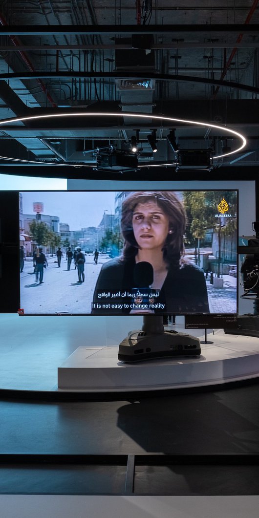 Photo of the Al Jazeera studio with a TV screen in the middle showing late Al Jazeera journalist Shireen Abu Akleh