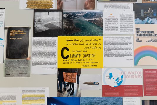 A collection of documents surround a yellow paper in the middle that has the word 'Climate Justice' written on it.