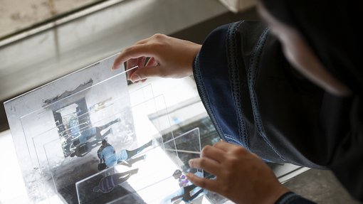 Artist Shaha Al-Khulaifi working on rearranging layers of photographs on glass in her studio.