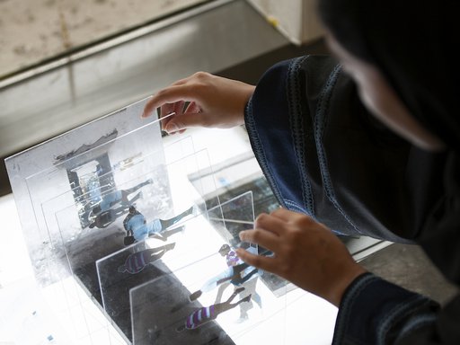 Artist Shaha Al-Khulaifi working on rearranging layers of photographs on glass in her studio.