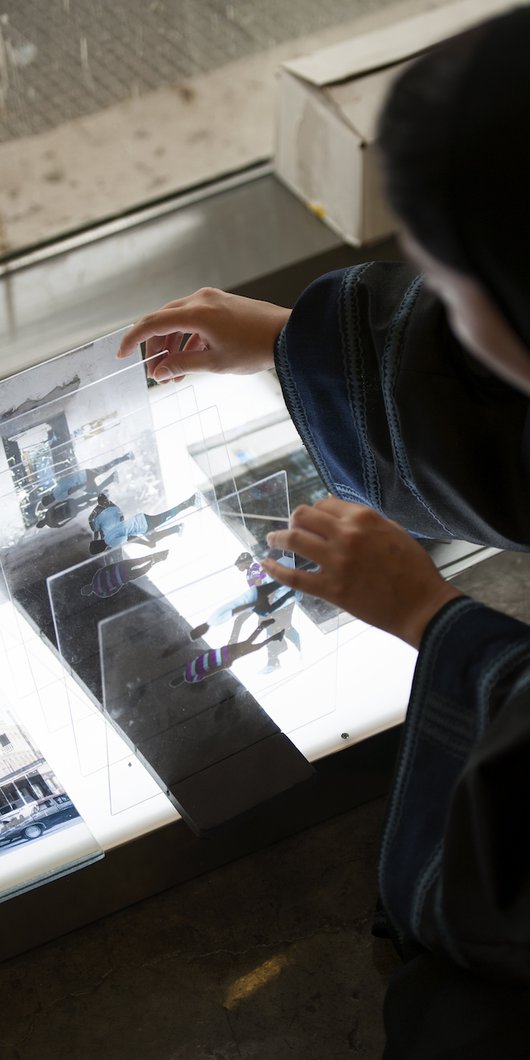 Artist Shaha Al-Khulaifi working on rearranging layers of photographs on glass in her studio.