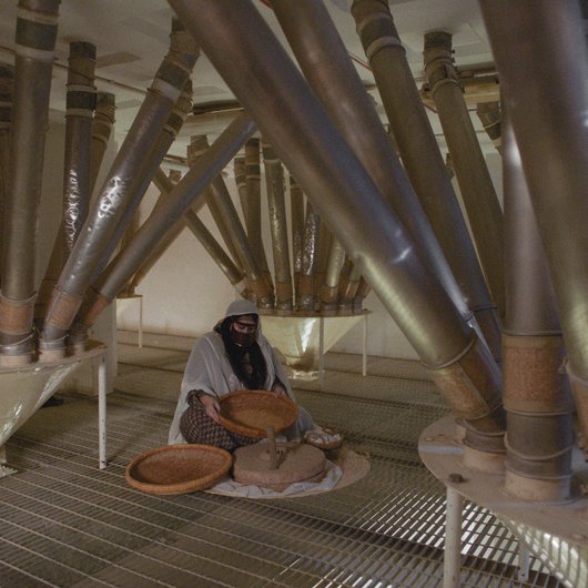 Woman in traditional Qatari dress making flour