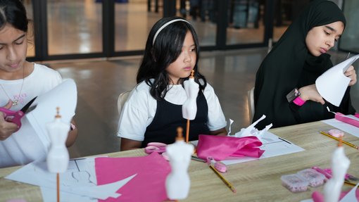 Girls sitting cutting fabric