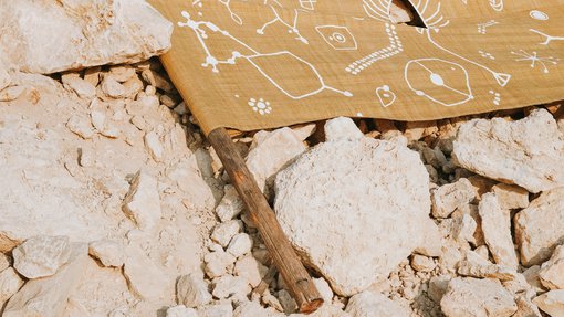 A shot of a brown kaftan, with white drawings laid on rocks.