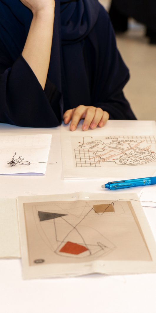 A close up of a table with sewing machine, pattern papers, and threads.