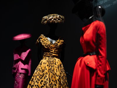 Three mannequins with Dior gowns.