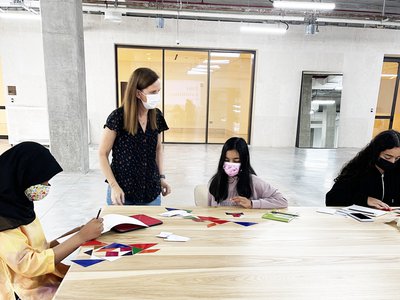 teacher with students around a table drawing