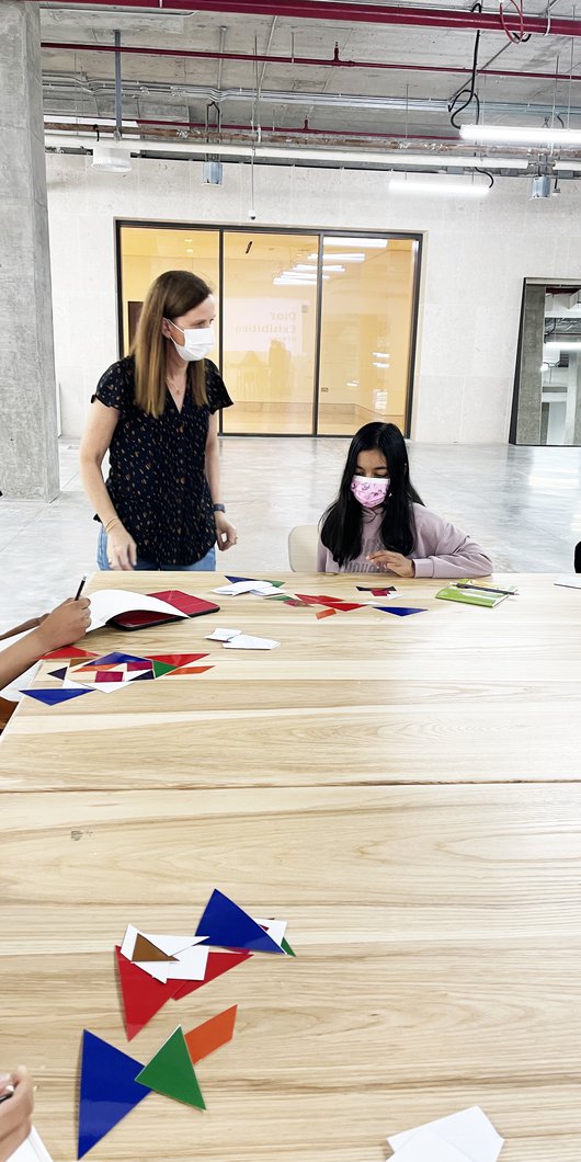 teacher with students around a table drawing