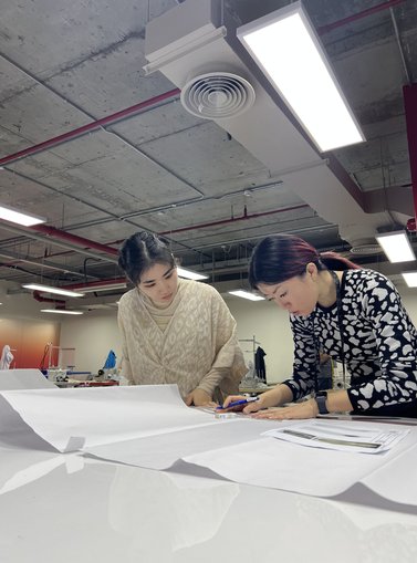 Two women sketching on a high table