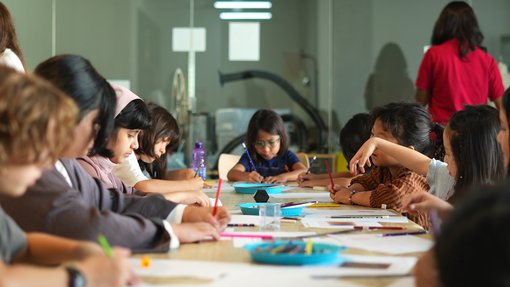 group of kids sitting on a table drawing