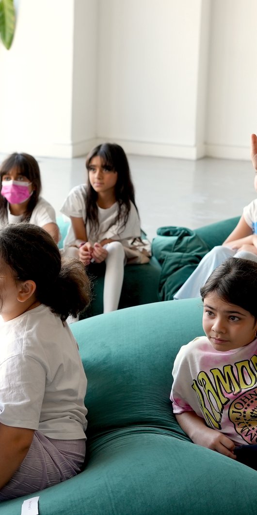 Group of kids sitting on a beanbag and some raising their hand