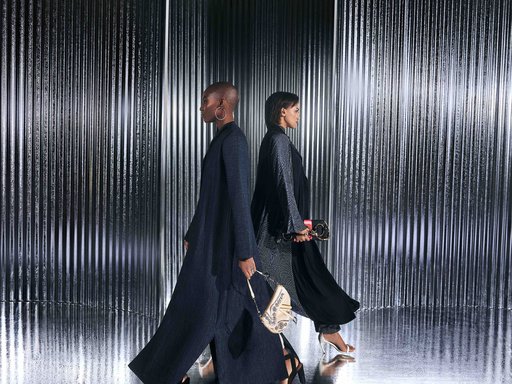 2 women walking side by side against a metal background