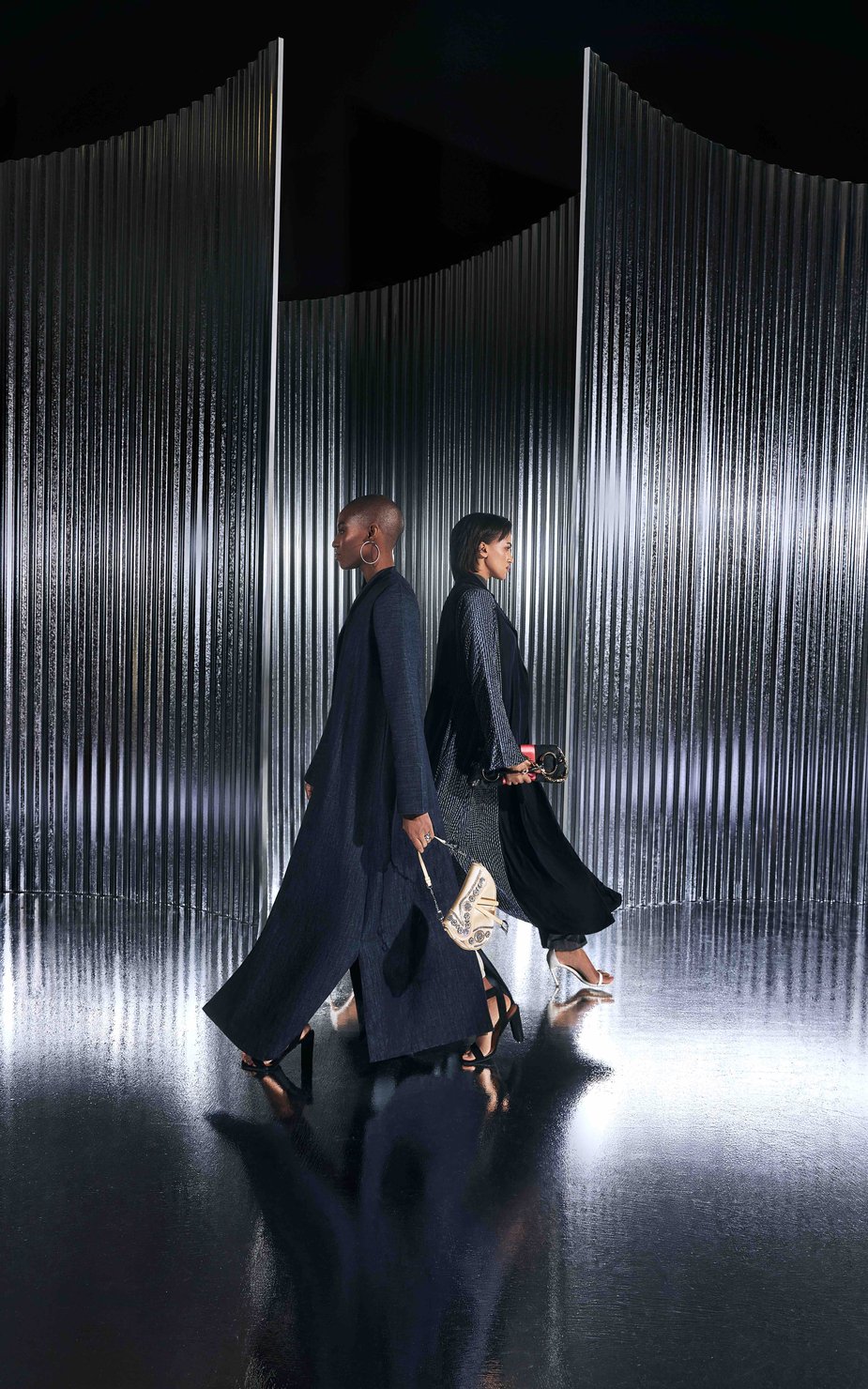 2 women walking side by side against a metal background
