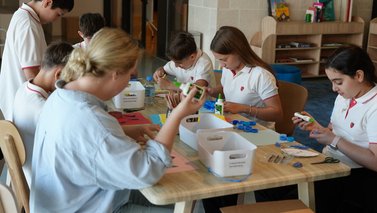 School kids sitting on a table doing crafts