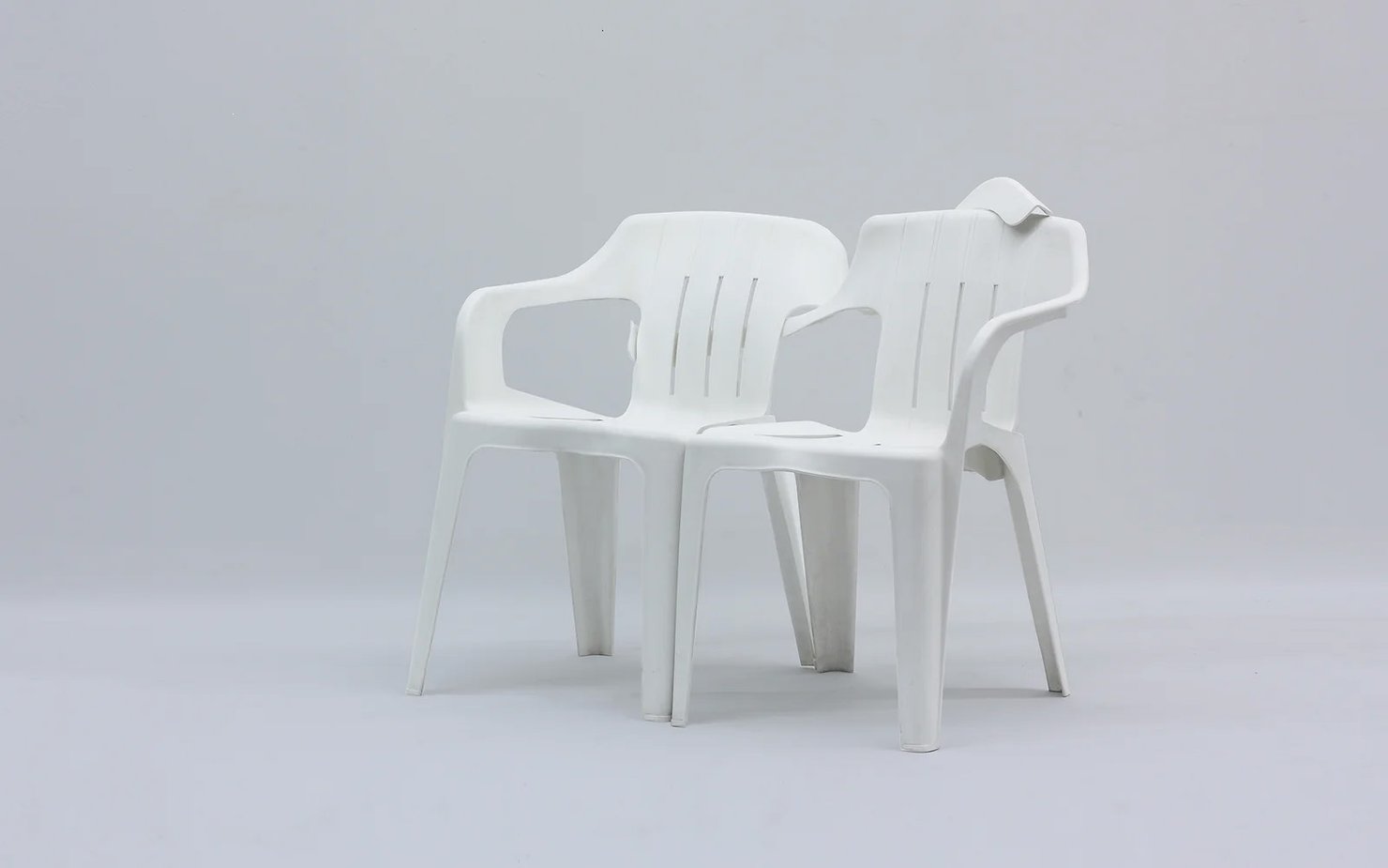 two white monobloc chairs hugging