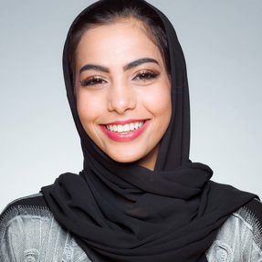 Sheikha Maryam Al Thani standing in front of grey wall