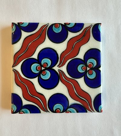 A piece of square tile with painted with abstract shapes