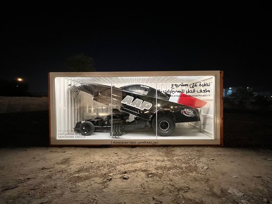 A black 2010 Toyota Camry AA/Fuel Funny Car with Qatar's flag attached in a display case