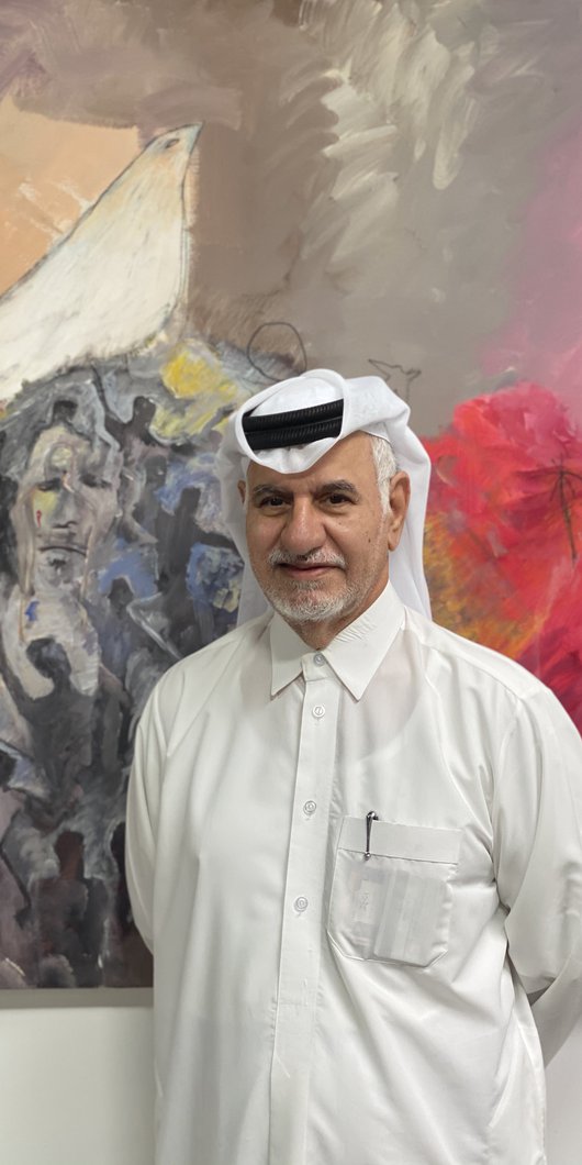 Ruwad Artist Hassan Al-Mulla standing next to his paintings in his studio at the Fire Station.