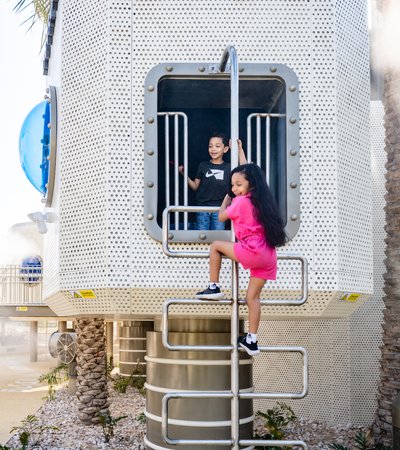 Children climbing on top of ladder to go on top of a tower that says ''use of liquified petroleum gas'' in Arabic