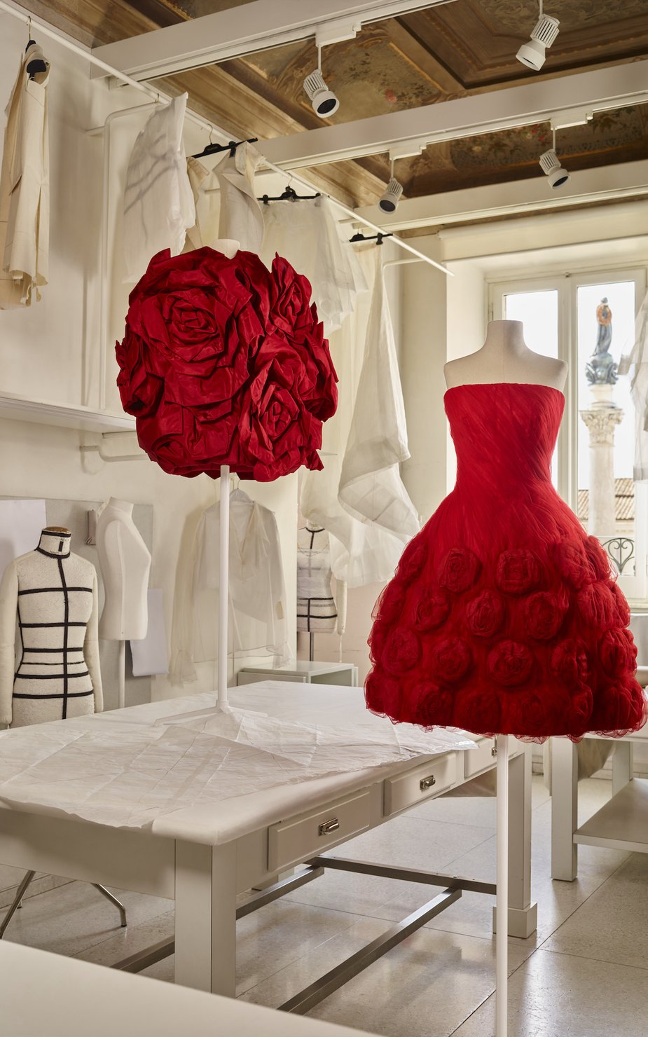 Two red Valentino dresses placed on mannequins in the Valentino workroom.