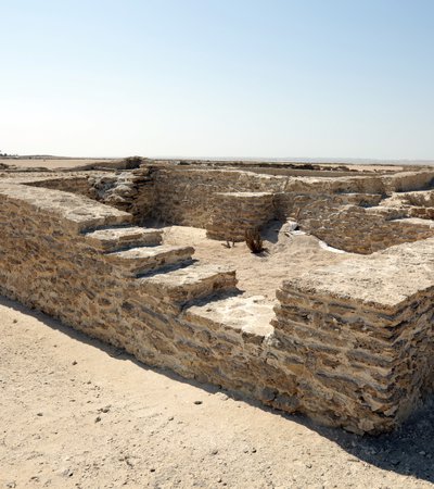 A stone structure on a beach with a visible set of stairs.