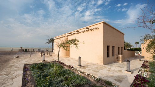 A complete view of the mosque with green patches and stoned flooring on the side