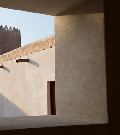 A close-up view from inside the Al Zubarah Fort showing its clay walls, wooden shafts and doors