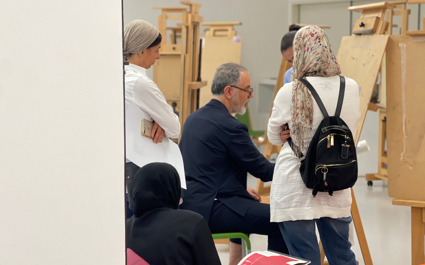 People observing Ismael Azzam as he is demonstrating a work on canvas stand