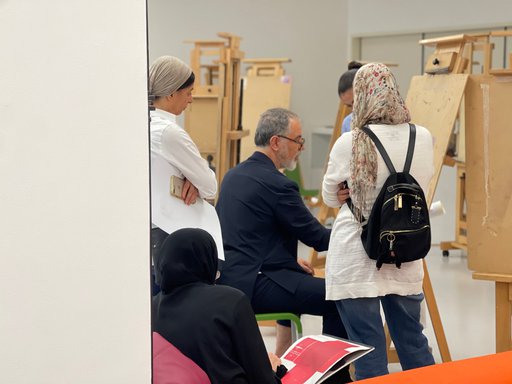 People observing Ismael Azzam as he is demonstrating a work on canvas stand