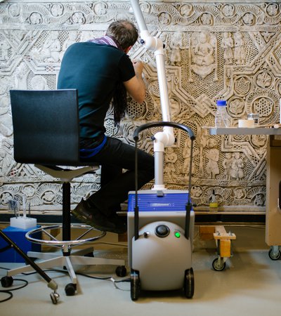 A man working to clean and conserve a decorative stone carving