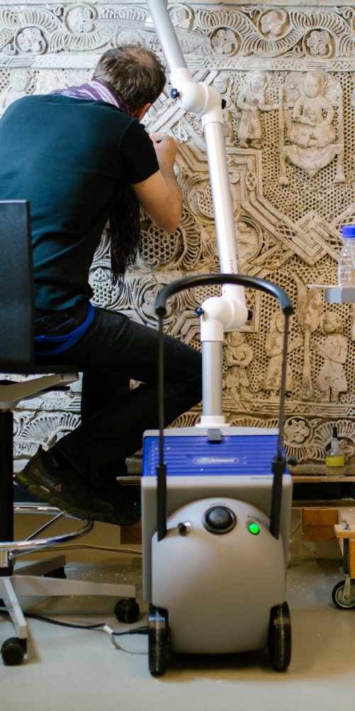 A man working to clean and conserve a decorative stone carving