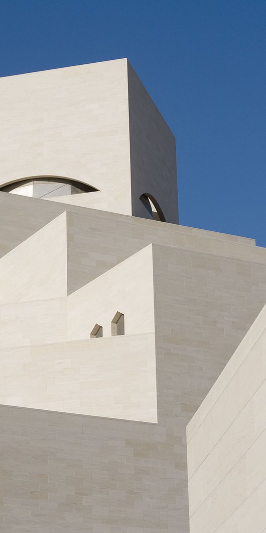 Detail of the white angular exterior of the Museum of Islamic Art with a blue cloudless sky in background