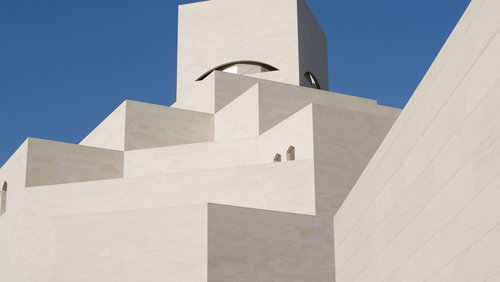 Detail of the white angular exterior of the Museum of Islamic Art with a blue cloudless sky in background