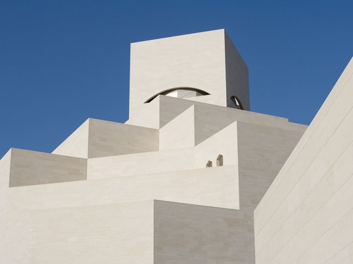 Detail of the white angular exterior of the Museum of Islamic Art with a blue cloudless sky in background