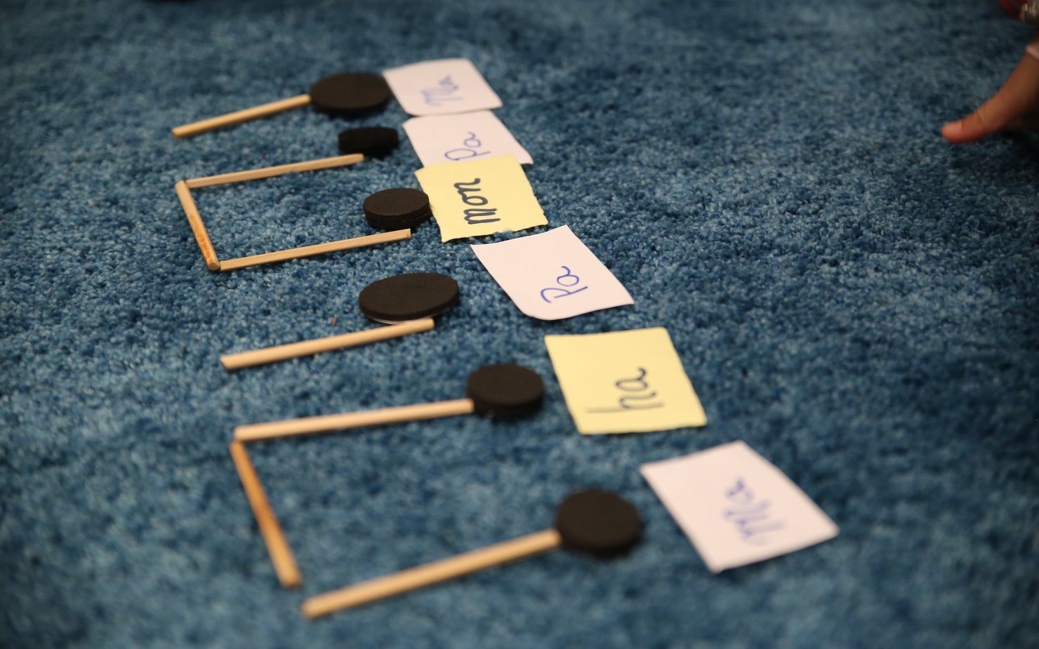 Small wooden sticks and black buttons are crafted as piano notes on a carpeted floor with the inclusion of written texts done on notes.