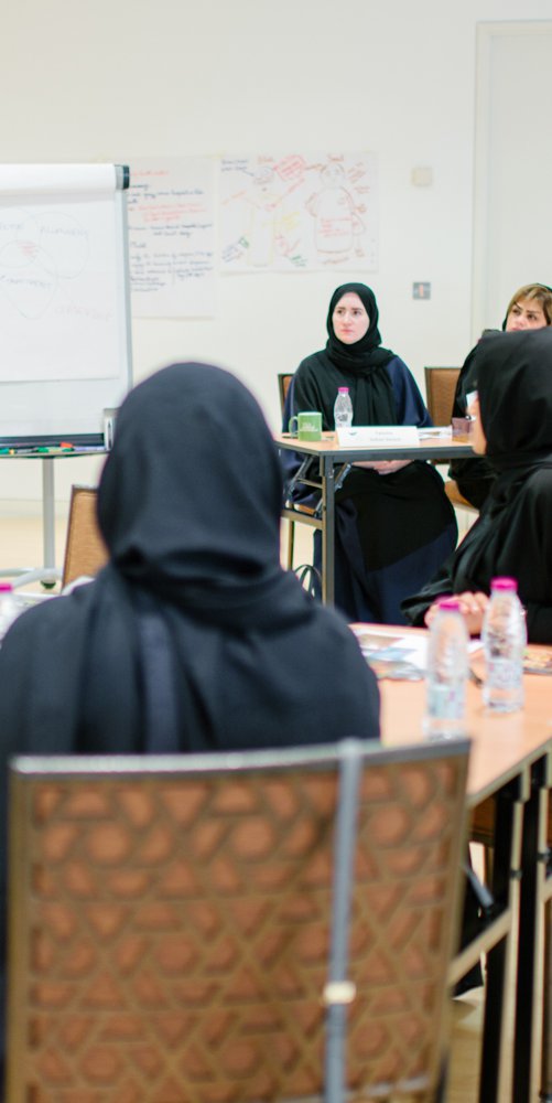 A teacher talks to adult students seated at desks