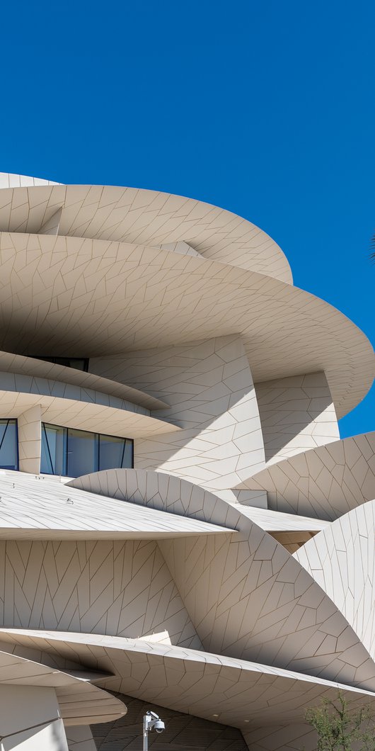 Exterior view of the National Museum of Qatar showing its angular disc like shapes against a blue sky