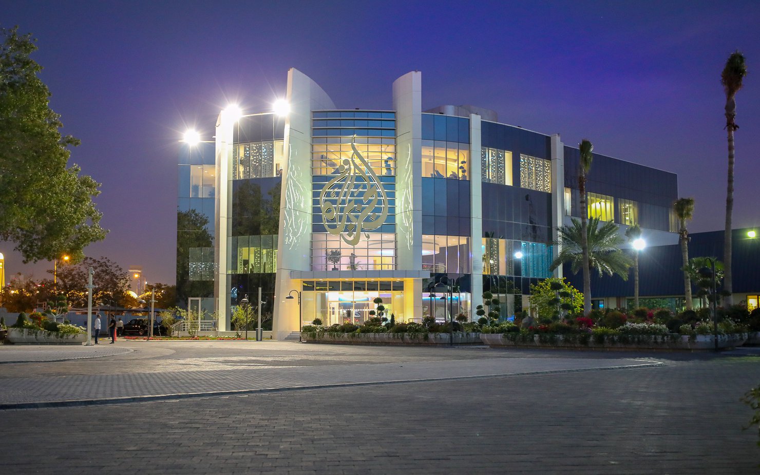 The outside of a building with the Al Jazeera logo mounted on the front.