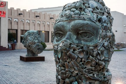 A close shot of two of the three sculptures showing heads wearing military gear, with one wearing a face cover and the other a gas mask