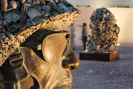 A focus on the sculptures wearing a soldier’s helmet and the other wearing a face cover