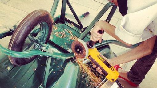 Hana Al Saadi wearing safety goggles and bending down to work on an upright wheelbarrow