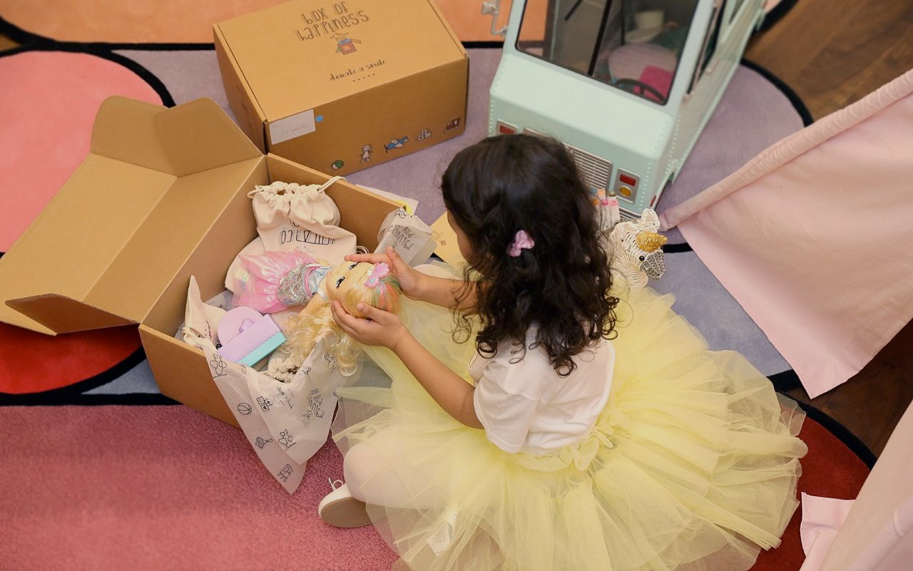 A girl in a yellow tutu dress playing with dolls