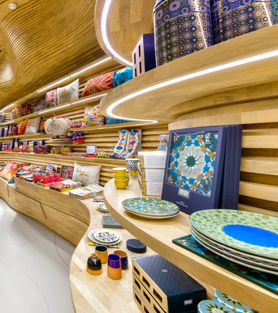 A dramatic view of the gift shop with local products displayed on curving wooden shelves at the National Museum of Qatar