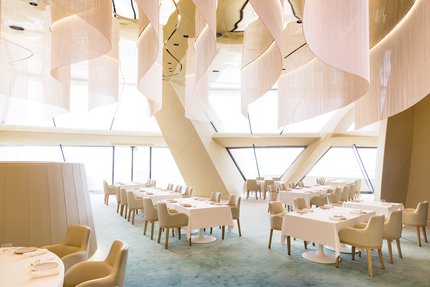 Interior view of Jiwan restaurant at National Museum of Qatar, showing table layout and interior architecture