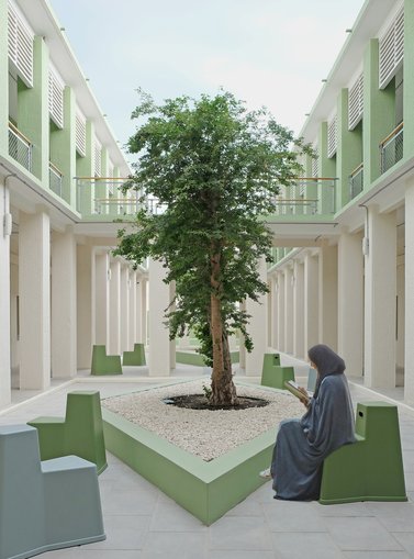 An open air courtyard, with contemporary seating and a woman reading.