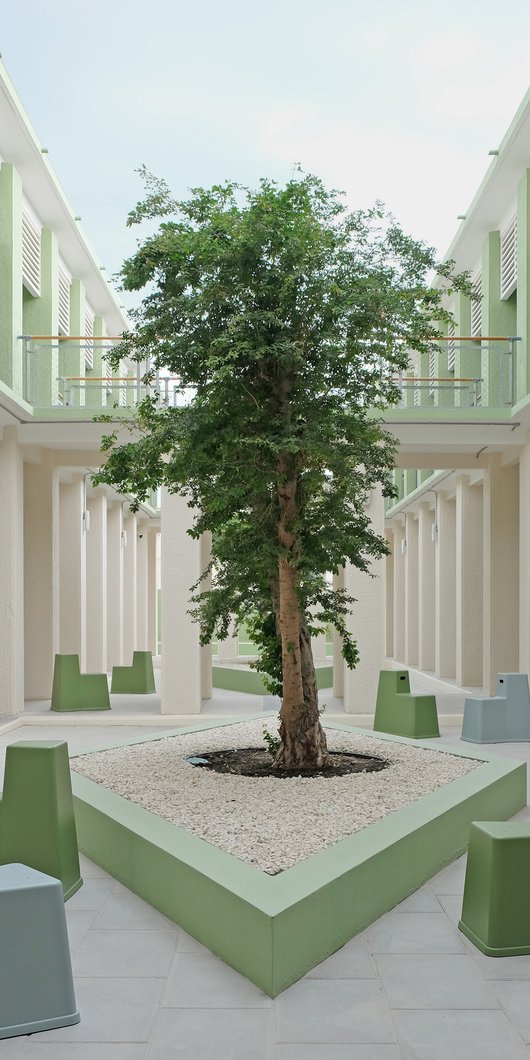 Exterior view of a courtyard with a tree and modern seating.