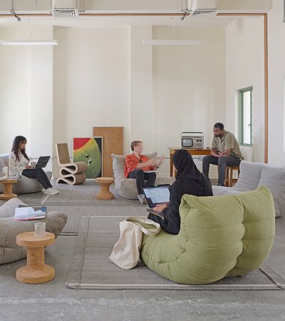 Indoor lounge area with large bean-bag style seating with people relaxing and talking.