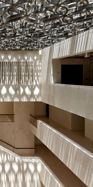 An interior shot of the M7 with light shining on intermingled staircases and fawn colours of the museum